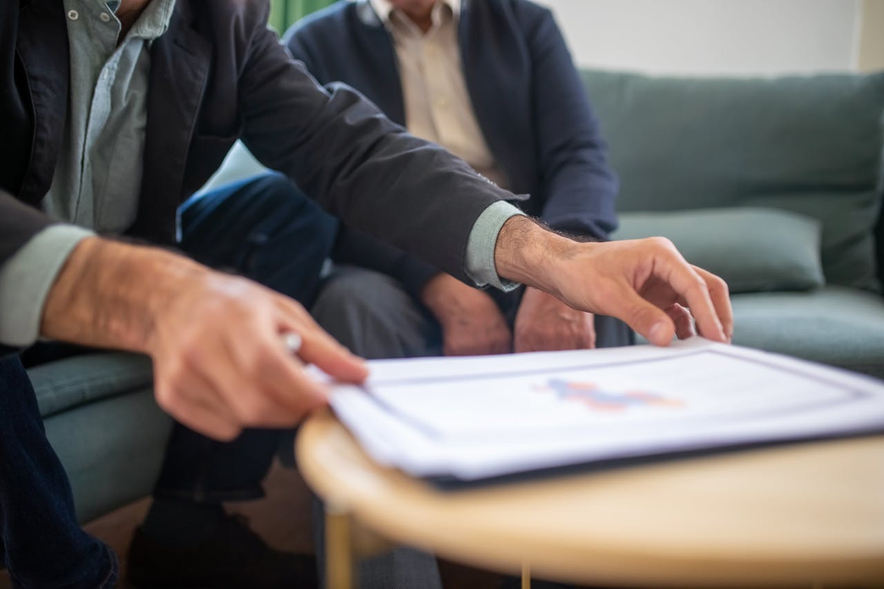 Two men discussing documents during a business meeting, focusing on paperwork.